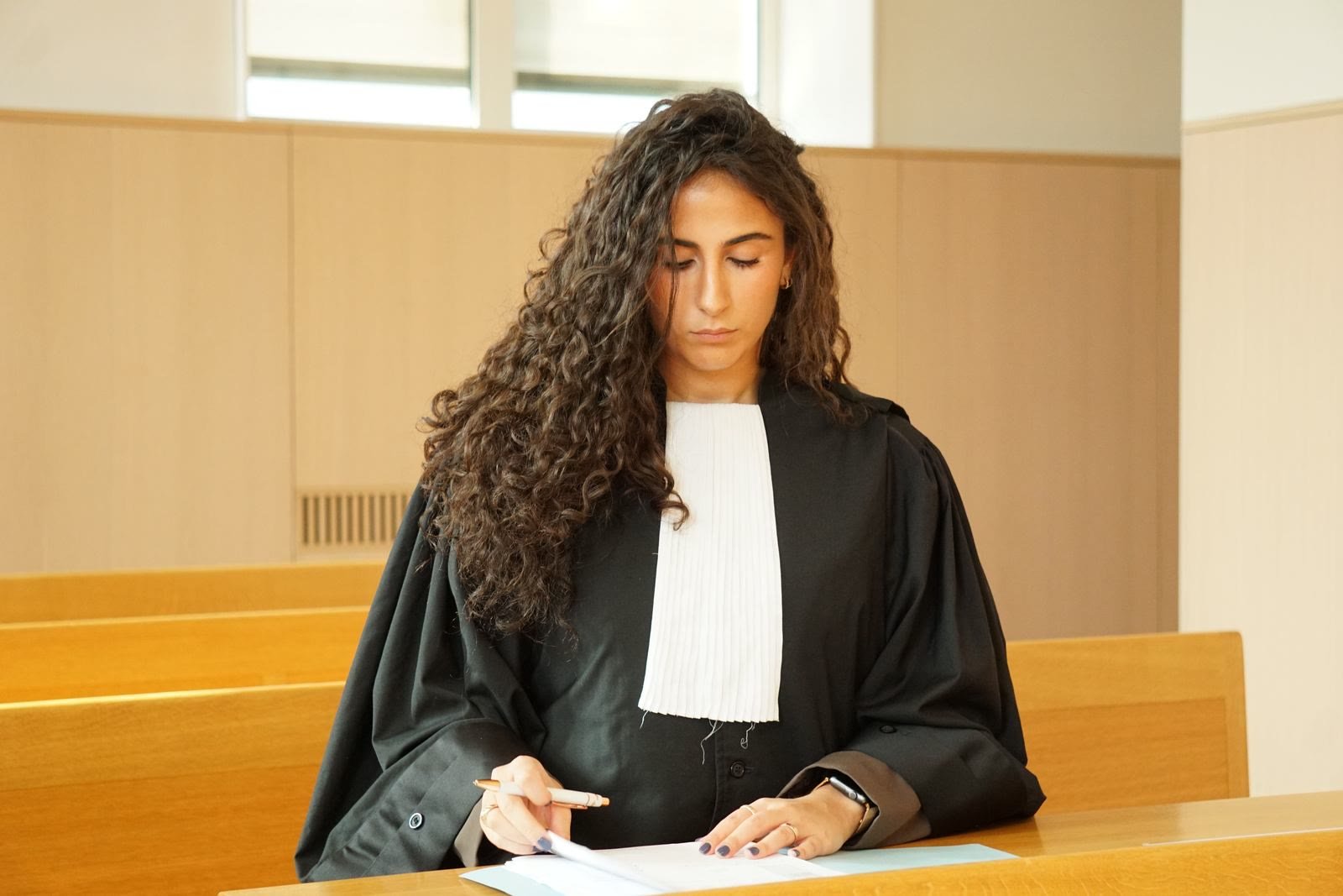 Mariam Kakulya en robe d'avocat, assise au banc, annotant un dossier